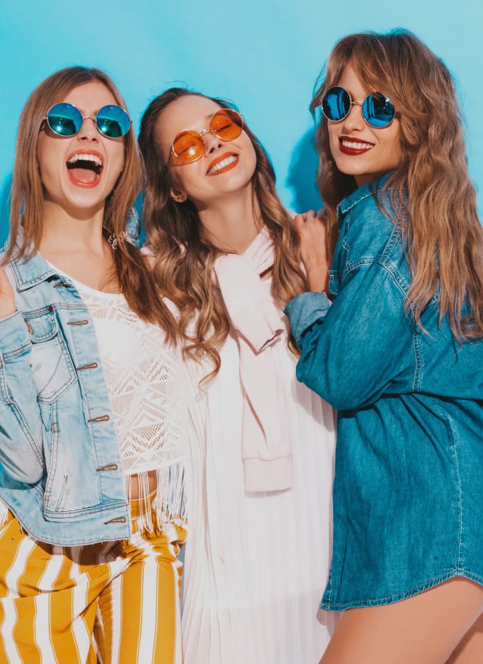 Three women wearing stylish outfits and sunglasses